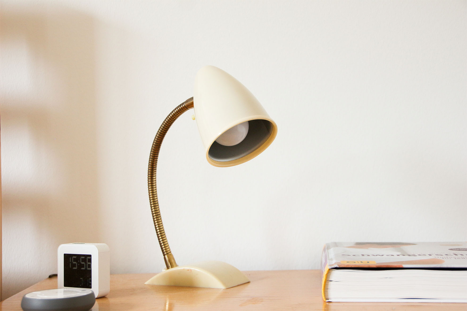 bedside light setup next to a clock and a book